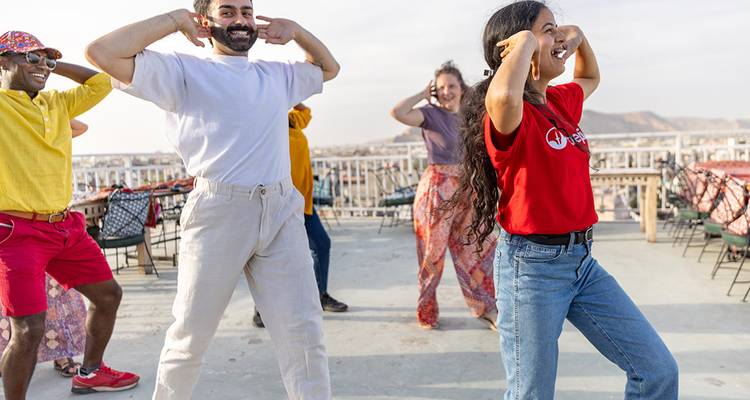 Los viajeros practican movimientos de baile en la azotea con las colinas del desierto a lo lejos de fondo