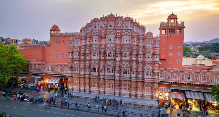 Ikonische rosa Fassade des Hawa Mahal, die im sanften Abendlicht erglänzt, mit Straßenleben darunter
