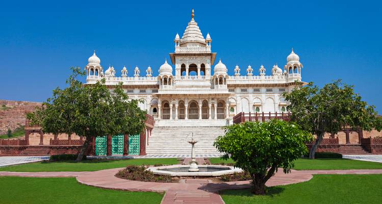 Vorderansicht von Jaswant Thada mit gepflegten Rasenflaechen, Springbrunnen und klarem blauem Himmel