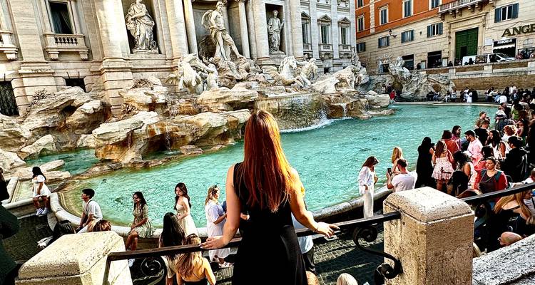 Een bezoeker staart naar het turquoise water van de Trevi-fontein terwijl menigten zich verzamelen rond de marmeren beeldhouwwerken.