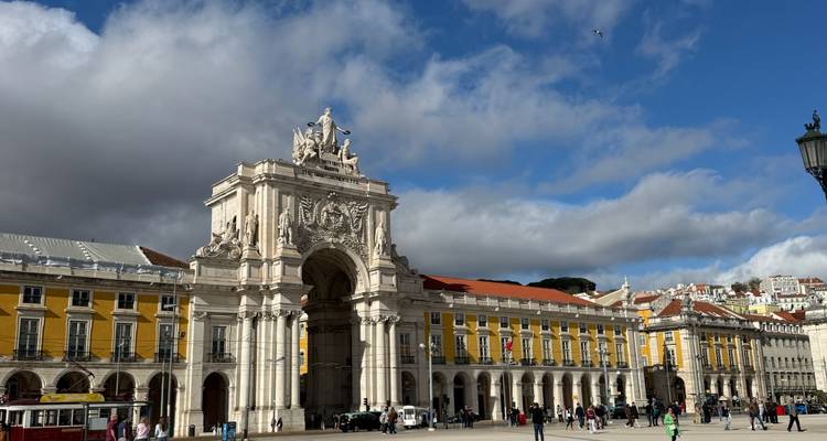 Grand Arco da Rua Augusta y edificios arcados amarillos enmarcando la Praça do Comércio de Lisboa llena de visitantes.