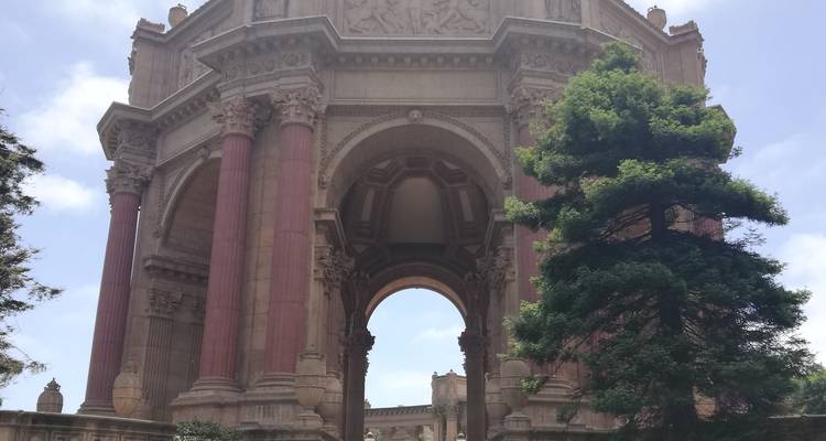 Grand rotonde classique avec de hautes colonnes roses à côté d'un grand arbre à feuillage persistant