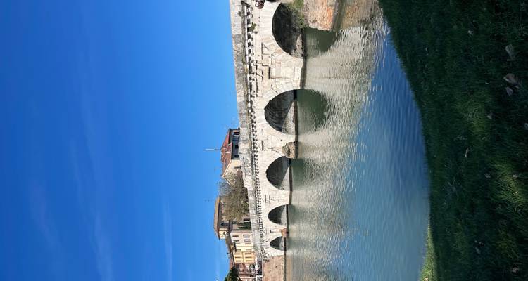 Pont en pierre à plusieurs arches historique enjambant une rivière calme sous un ciel bleu dégagé