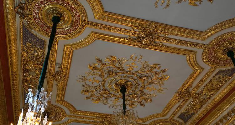 Un plafond blanc et or opulent orné de lustres en cristal met en valeur une ornementation Baroque somptueuse.
