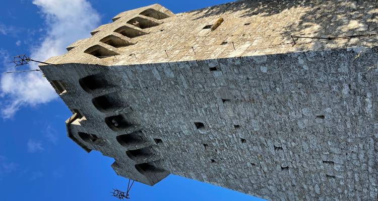 tour de guet médiévale en pierre s'élevant vers un ciel bleu avec des structures d'antenne au sommet