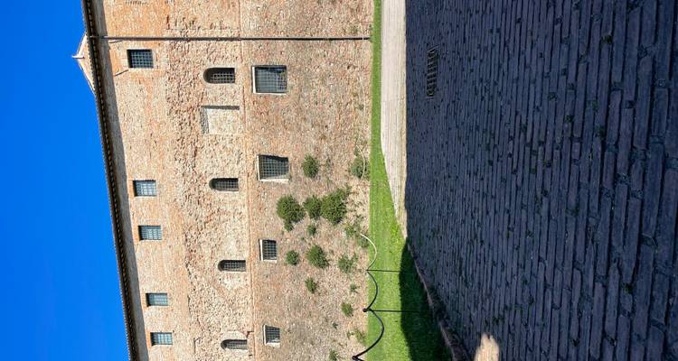 mur de forteresse en brique avec de petites fenêtres et premier plan pavé sous un ciel bleu