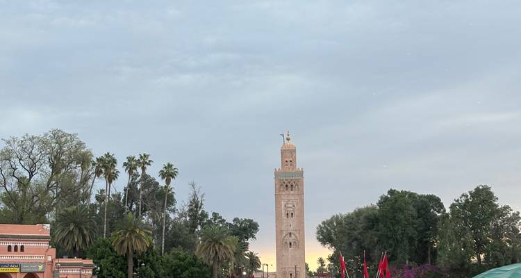 Minarete Koutoubia enmarcado por palmeras al atardecer con una luz cálida tenue