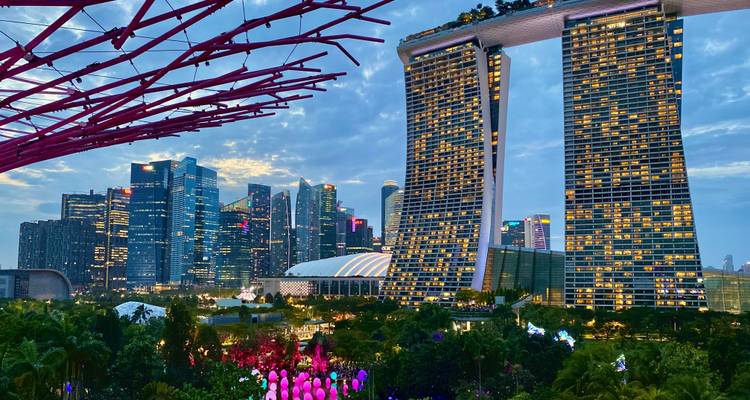 Les tours de Marina Bay Sands s'élèvent au-dessus de jardins illuminés et de la skyline du centre-ville de Singapour à l'heure bleue.