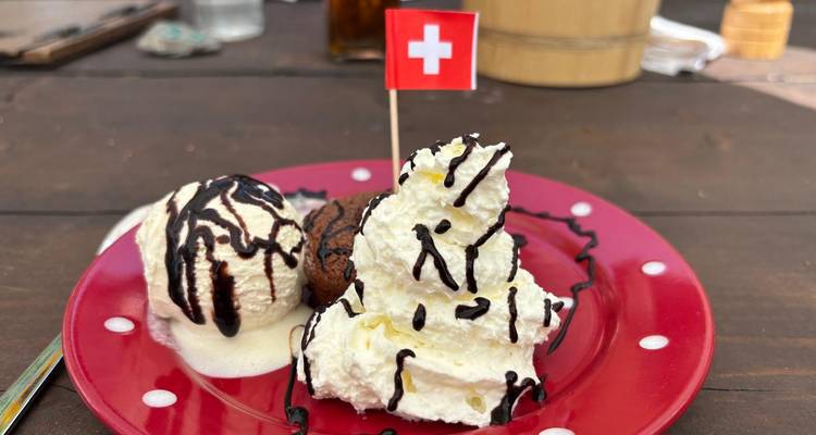 Assiette de dessert de crème glacée suisse avec filet de chocolat et petit drapeau suisse sur table en bois