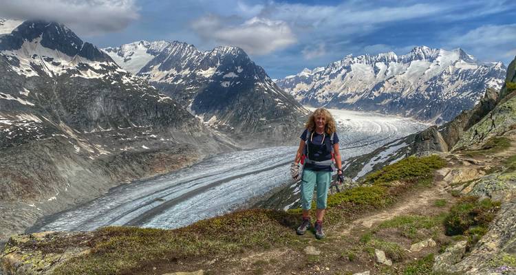 Femme randonneuse posant sur une crête surplombant un vaste glacier et des pics enneigés spectaculaires en Suisse
