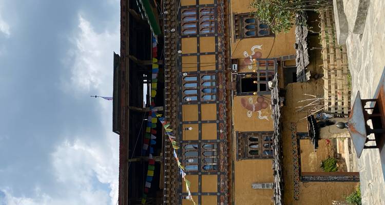 Monastère ou maison bhoutanais traditionnel avec des drapeaux de prière sous un ciel nuageux