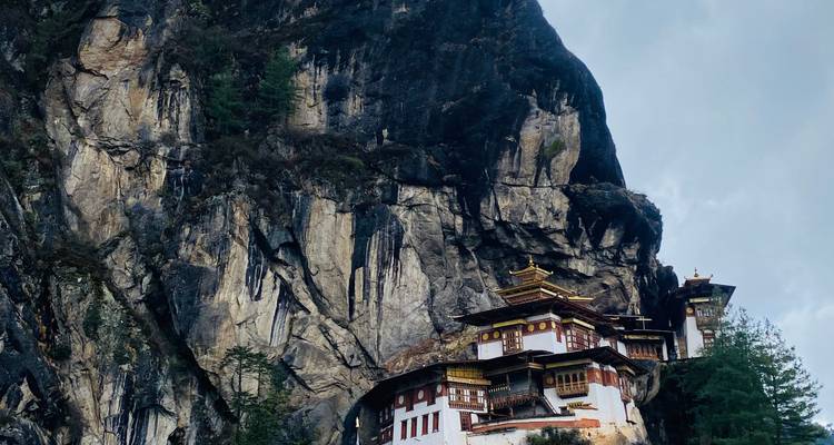 Gros plan en plongée du monastère de la Tanière du Tigre sous un ciel chargé mettant en évidence la falaise spectaculaire