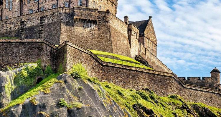 Indrukwekkende stenen muren en torentjes van Edinburgh Castle trotseren vanaf vulkanisch gesteente de blauwe lucht.
