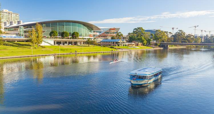El bote turístico se desliza por el río Torrens junto al Centro de Convenciones de Adelaida con remeros de fondo