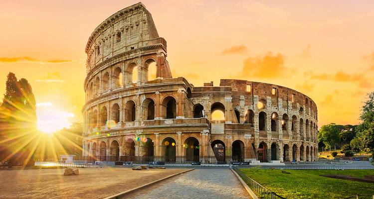 Het Colosseum gloeiend in warm zonsondergangslicht met zonnestralen die langs oude bogen pieken.