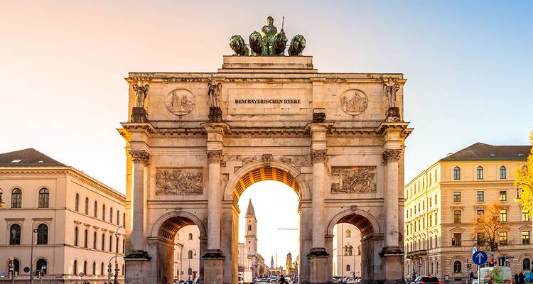 De Siegestor triomfboog van München omgeven door neoklassieke gebouwen in warm avondlicht.