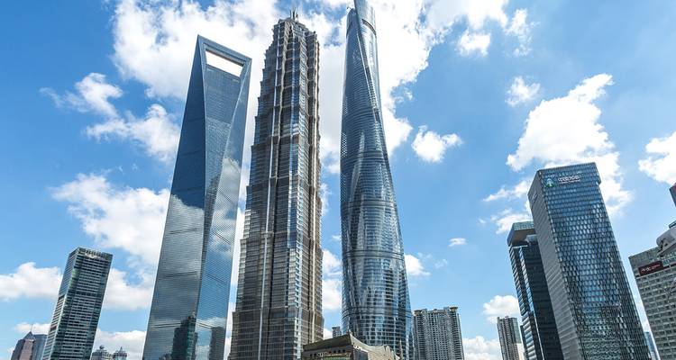 La skyline emblématique de Pudong avec la Shanghai Tower, la Jin Mao Tower et le Shanghai World Financial Center sur fond de nuages lumineux.