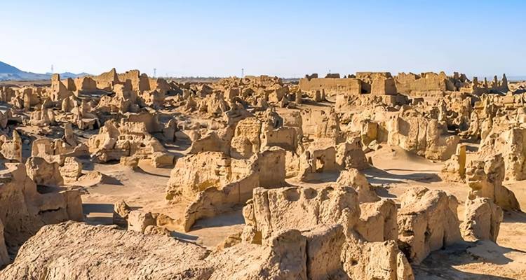 Ruinas expansivas de una antigua ciudad de adobe bajo un cielo azul despejado en un entorno desértico.