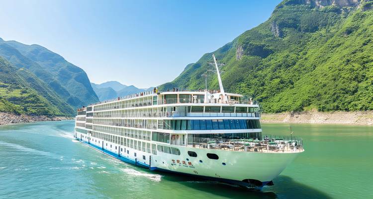 Un gran crucero fluvial blanco navega por aguas esmeraldas entre montañas verdes escarpadas.