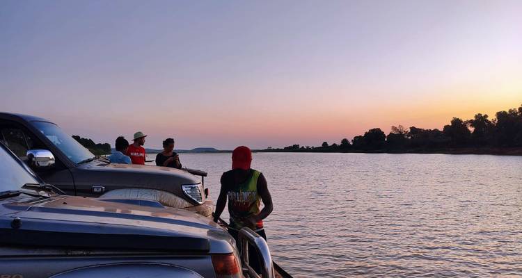 Les voyageurs sur le pont des véhicules d'une péniche glissant sur un large fleuve au coucher de soleil coloré