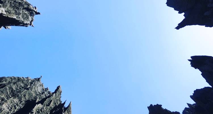 Composition vers le ciel encadrée par des aiguilles de roche tsingy acérées créant une bordure naturelle