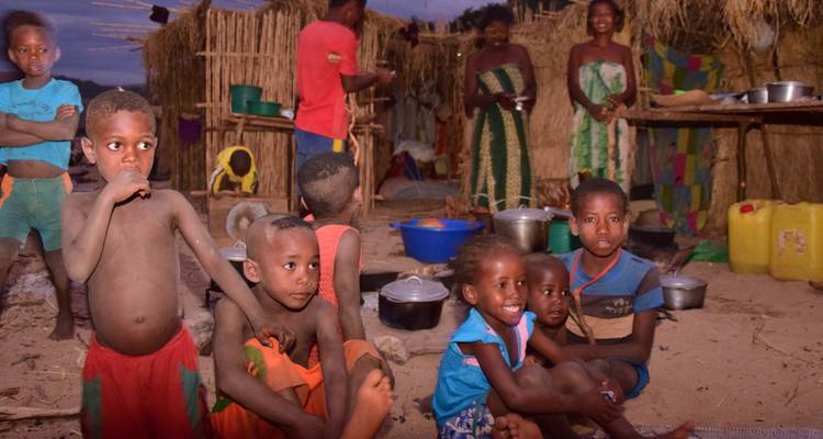 Les enfants du village local assis et debout autour d'une zone de cuisson extérieure au crépuscule