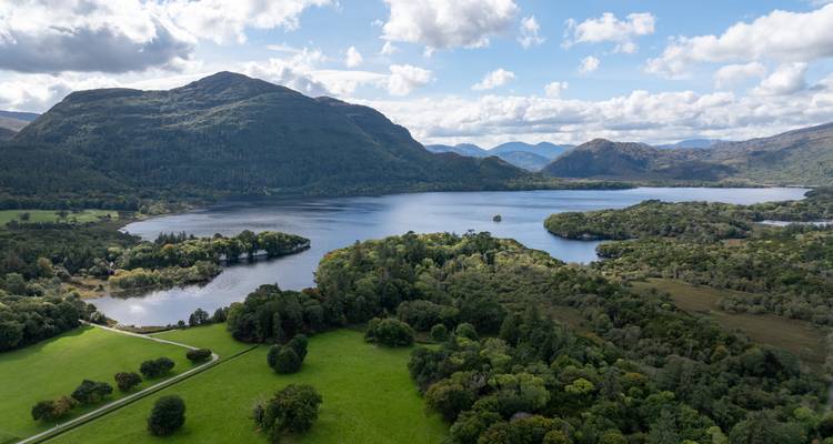 Vue aérienne d'un lac serein entouré de collines boisées et de pâturages verdoyants luxuriants en Irlande