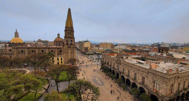 Vue panoramique aérienne du centre historique de Guadalajara avec la flèche de la cathédrale, des places verdoyantes et des rues animées.