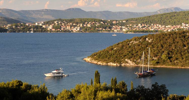 Yachts naviguant dans une baie adriatique bleue entourée de collines verdoyantes près de Trogir
