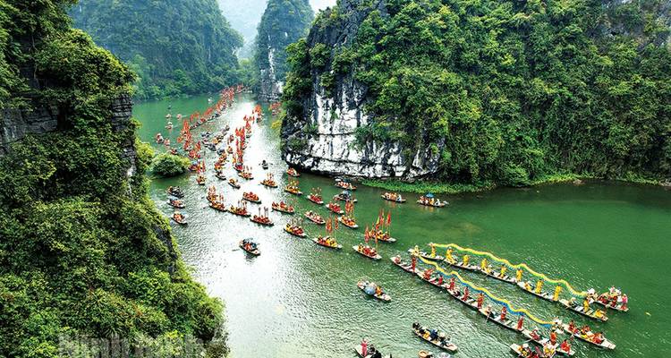 Des centaines de bateaux-dragons colorés et de participants au festival alignés le long d'une gorge fluviale verdoyante