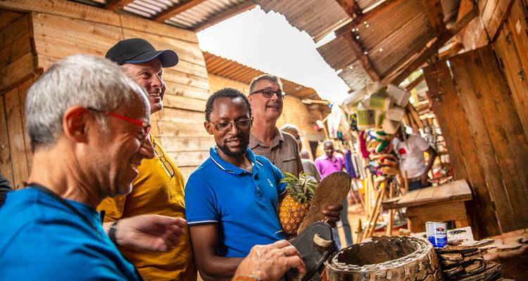 Des touristes interagissent avec un vendeur local à l'intérieur d'un étal de marché rustique en bois, examinant de l'artisanat et des fruits.