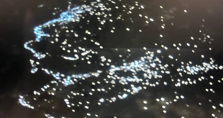 Image floue abstraite de lumières blanches dispersées sur un fond sombre sans sujet clairement défini.