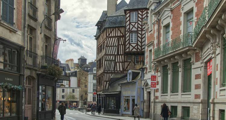 Rue historique à Rennes bordée de bâtiments à colombages et de boutiques élégantes.