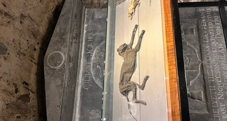 Historical display of a mummified cat and rat under glass in a crypt setting with carved stone backdrop.