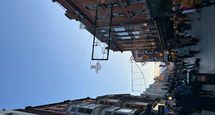 Daytime shopping street crowded with pedestrians and festive chandeliers strung overhead.
