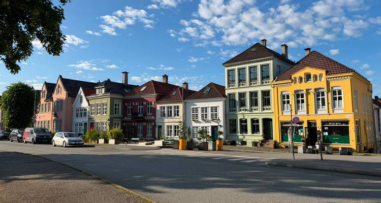 Rangée de maisons historiques colorées sous un ciel bleu éclatant dans une rue résidentielle tranquille.