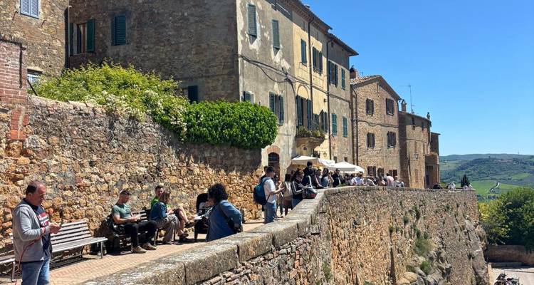 Ruelle pavée d'une ville toscane historique avec des touristes assis sur des bancs et se promenant