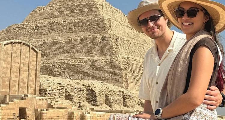 Pareja posando felizmente frente a la Pirámide Escalonada de Saqqara en un día soleado