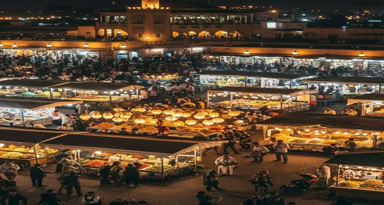 El bullicioso mercado nocturno de Jemaa el-Fnaa iluminado por cientos de linternas y lleno de visitantes y puestos de comida.