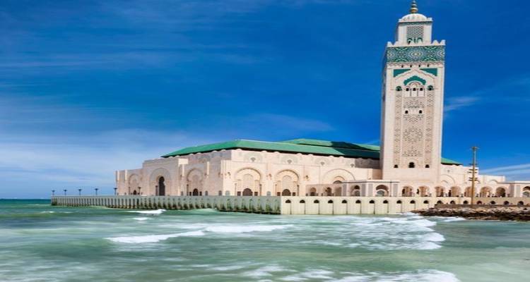 La Mezquita Hassan II se alza majestuosamente sobre el Atlántico con olas chocando contra su muro de contención.