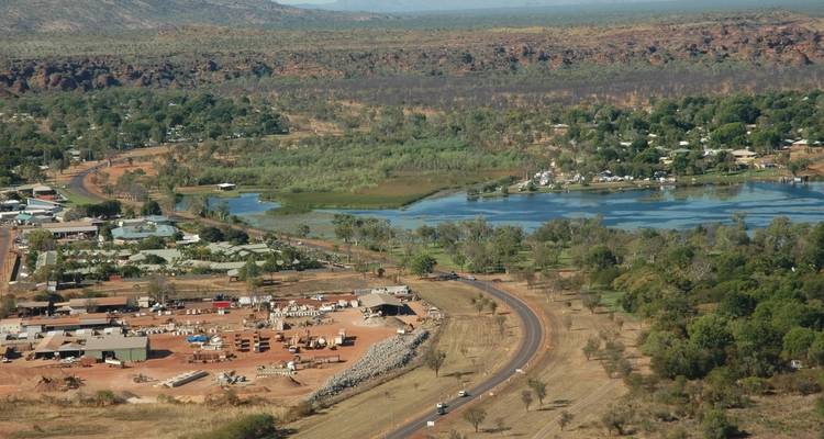 Vista aérea panorámica de un pueblo del interior junto al río con humedales verdes y acantilados rojos a lo lejos