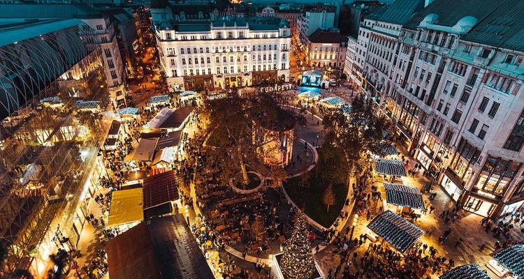 Vue aérienne au crépuscule d'un marché de Noël européen animé remplissant une grande place de la ville avec des lumières et des étals.