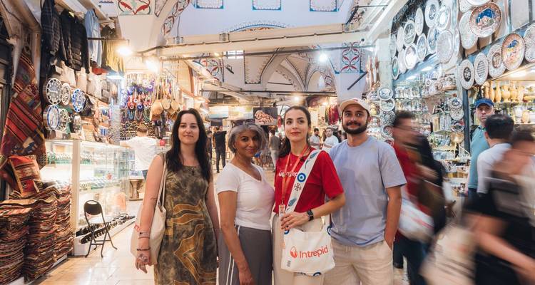 Reizigers poseren tussen de kleurrijke drukke gangen van de Grote Bazaar van Istanboel, omzoomd met keramiek en textiel.