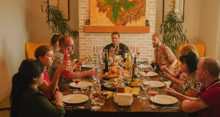 Freunde und Familie versammelten sich an einem Esstisch im Inneren, um ein reichhaltiges Mahl und Wein zu genießen.