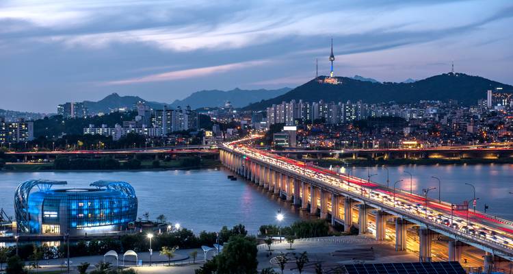 Nachtblick über den Han-Fluss in Seoul mit beleuchteter Brücke und dem Namsan-Turm in der Skyline.