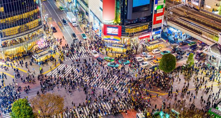 Nächtliche Luftaufnahme der Shibuya Crossing in Tokio voller Fußgänger und Neonlichter.