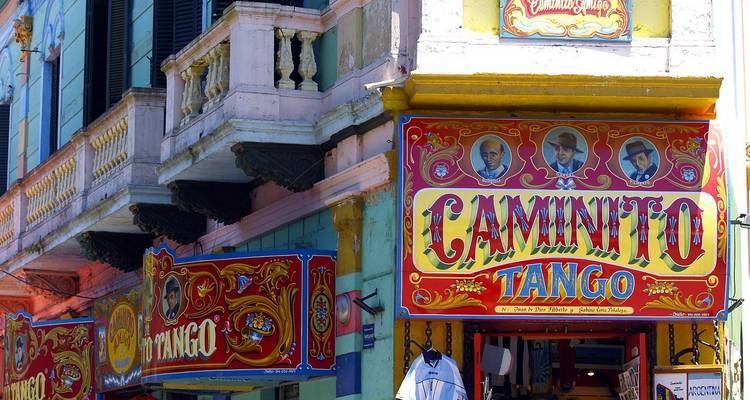 Frentes de tiendas pintadas con colores brillantes con señalización ornada de 'Caminito Tango' y fachadas coloridas.