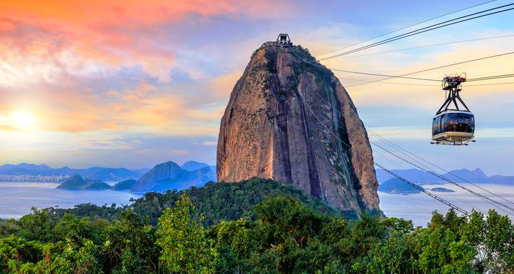 Vistas espectaculares del atardecer en el Pan de Azúcar con un teleférico deslizándose sobre el bosque frondoso y las aguas del Atlántico.