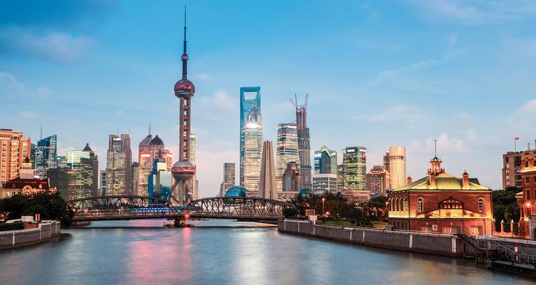 Die ikonische Skyline von Shanghai mit dem Oriental Pearl Tower und modernen Wolkenkratzern, die sich bei Einbruch der Dämmerung in der Huangpu River spiegeln.