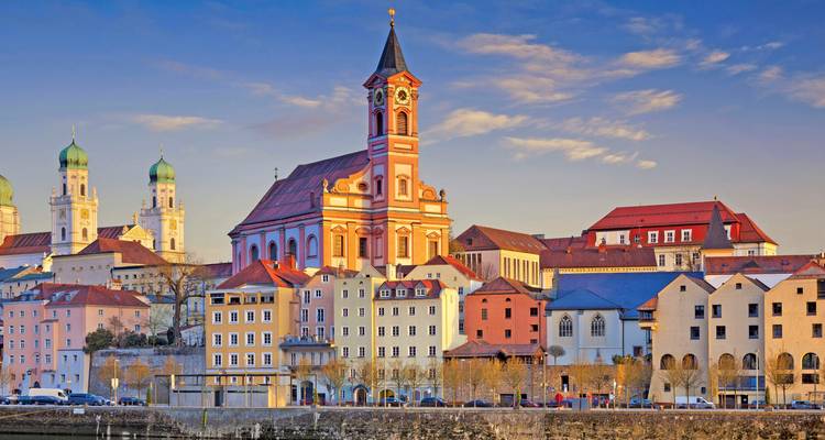 Vista de la hora dorada del colorido frente fluvial de Passau y las torres de iglesias barrocas reflejadas en el Danubio.